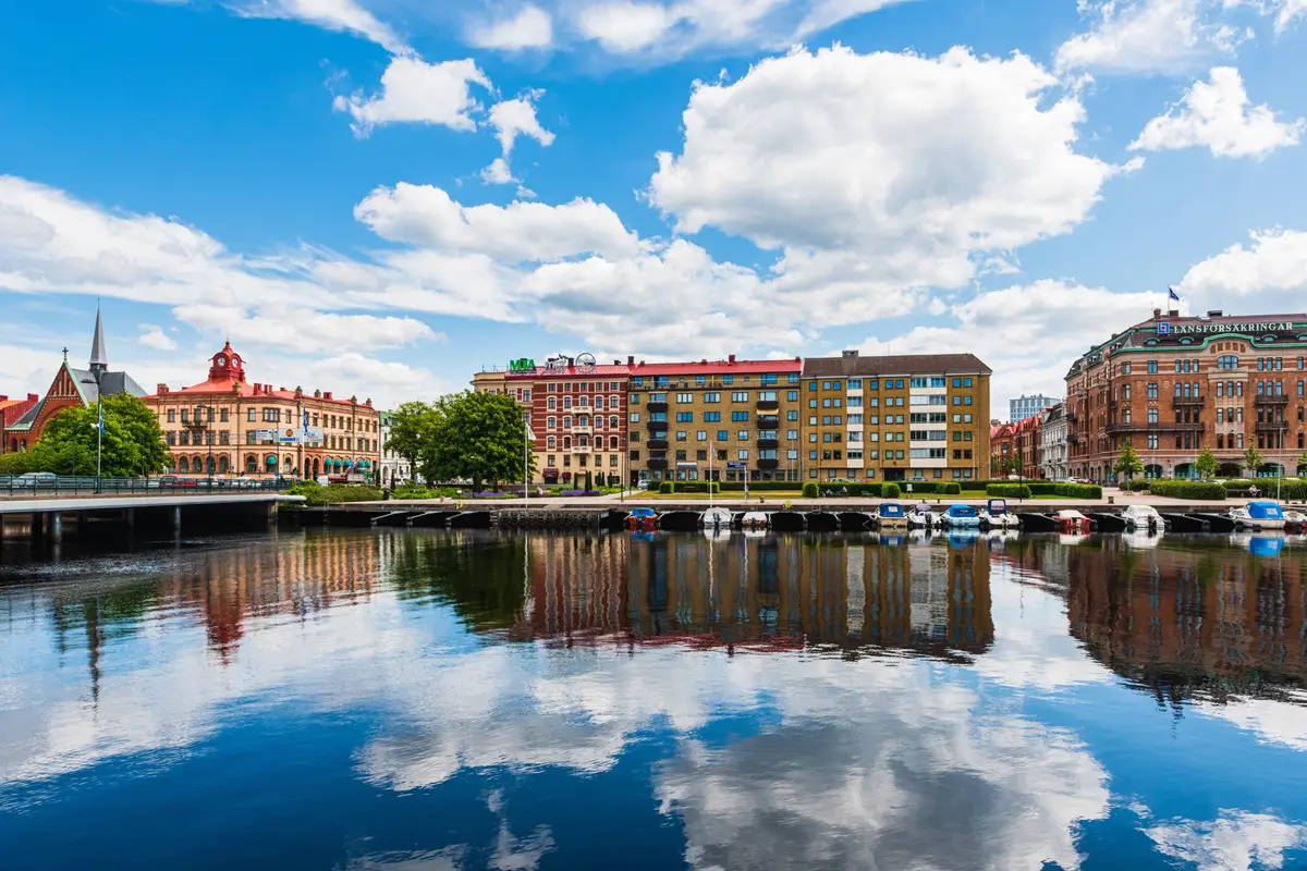 Colorful buildings of Halmstad Sweden reflecting in the calm waters of a river, showcasing Scandinavian architecture and urban calmness.