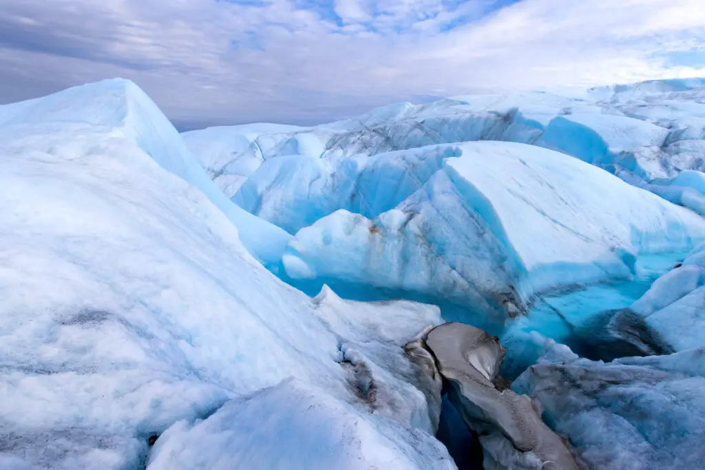 Stunning blue ice formations on the Greenlandic ice cap, showcasing deep crevasses and undulating waves of ice during an overnight expedition.