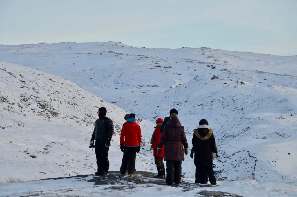Tourists walking on Point 660 glacier near Kangerlussuaq in Greenland's stunning winter landscape.