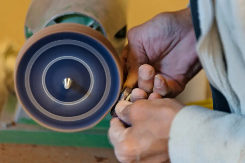 Artisan in Sisimiut, Greenland, carefully polishing a muskox bone on a spinning wheel for crafting traditional items